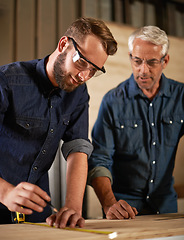 Image showing Wood, learning and carpentry apprentice with mentor in designer furniture manufacturing workshop. Mentorship, senior carpenter and young man, measuring tape and focus on teaching sustainable business