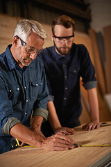 Image showing Teaching, learning and carpentry apprentice with measuring tape in designer furniture manufacturing workshop. Mentorship, carpenter and young man, wood measurement and sustainable business project.