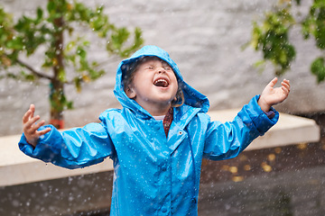 Image showing Winter, rain coat and a girl playing in the weather outdoor alone, having fun during the cold season. Children, water or wet with an adorable small female kid standing arms outstretched outside