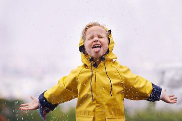 Image showing Winter, raincoat and a girl tasting the rain outdoor alone, having fun during the cold season. Kids, water or wet with an adorable little female child playing arms outstretched outside in the day