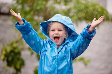 Image showing Winter, raincoat and a happy girl playing in the rain outdoor alone, having fun during the cold season. Kids, water or wet with an adorable little female child standing arms outstretched outside