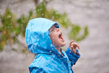 Image showing Winter, raincoat and a girl having fun in the rain outdoor alone, playing during the cold season. Kids, water or wet weather with an adorable little female child standing arms outstretched outside