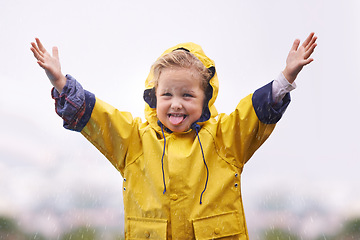 Image showing Winter, raincoat and a girl playing in the water outdoor alone, having fun during the cold season. Kids, rain or wet with an adorable little female child standing arms outstretched outside in the day