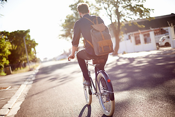 Image showing Bicycle, transport and back of man in street on lens flare for exercise, commute and cycling in morning. Travel, city and male cyclist on bike for eco friendly traveling, carbon footprint and journey