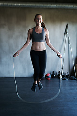 Image showing Smile, jump rope and happy woman doing gym training, cardio endurance challenge or exercise performance. Skipping, fitness energy and sports person, female athlete or girl doing jumping exercises