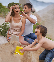 Image showing Family, laughing and sand castle at beach in summer for fun, travel or holiday with love. A man, woman and excited kid playing together on vacation at sea with a toy bucket, development and happiness