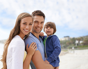 Image showing Family, child and portrait outdoor at beach for travel, adventure or holiday in summer with a smile. A man, woman and kid or son together on vacation at sea with a blue sky, parents and happiness
