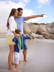 Image showing Family, child and pointing outdoor at beach for travel, adventure or holiday in summer with a smile. A man, woman and kid or son together on vacation at sea for blue sky, learning and happiness