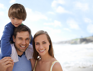 Image showing Happy family, portrait and blue sky at beach on travel, holiday or vacation in summer with a smile. Man, woman and child together on adventure or quality time at sea with happiness, love and care