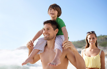 Image showing Family, child and walking outdoor on beach for travel, fun or holiday in summer with a smile. Man, woman and child on shoulders for vacation, adventure or walk at sea with happiness, love and care