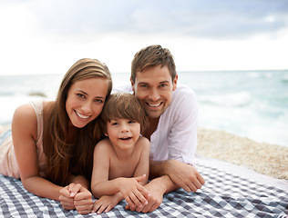 Image showing Beach, family and portrait outdoor in summer on a picnic blanket for travel vacation to relax. Smile of a man, woman and child or son happy together on holiday at sea with love, care and happiness