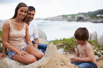 Image showing Family, child and sand castle portrait at beach in summer for fun, travel or holiday. A man, woman and kid playing together on vacation at sea for quality time, development and happiness outdoor