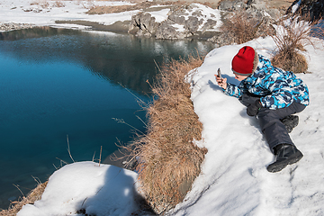 Image showing Young boy taking photos on the coast river