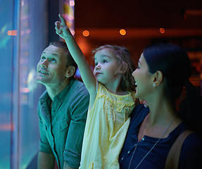 Image showing Family, aquarium and child pointing at fish for learning, curiosity or knowledge, bonding or care. Mother, fishtank and happy kid with father watching marine animals swim underwater in oceanarium.