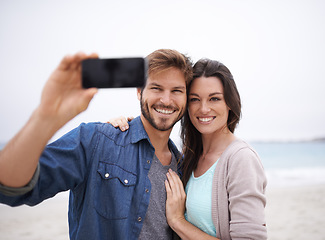 Image showing Selfie, love and couple hug at beach for travel, photo and freedom outdoors together. Smile, embrace and traveling influencer people live streaming for blog, followers or social media profile picture