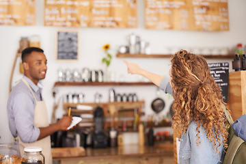 Image showing Woman, coffee shop and pointing at menu on wall with barista, notes and service for good customer experience. Male waiter writing, lady and talking with choice, decision and order from bakery shop