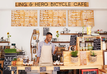 Image showing Black man, cafe sign and phone of an entrepreneur with happiness from small business. Coffee shop, mobile and African barista looking on an app with a smile at bakery and restaurant feeling happy