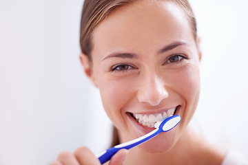 Image showing Young woman, portrait and brushing teeth in bathroom with smile, health or self care for hygiene, grooming and routine. Girl, toothbrush and happiness for cleaning, healthy mouth and start morning