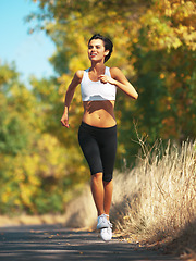 Image showing Woman is running on road, cardio and fitness outdoor in nature with healthy and active person. Sport, exercise and body training for marathon, young female runner workout for health with energy