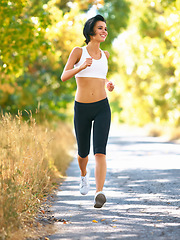 Image showing Woman is running in road, sport and fitness outdoor with fit body, healthy and active person. Cardio, exercise and training for race, young female runner in nature with workout for health