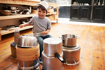 Image showing Portrait, boy child and playing drum on a pot on a floor, happy and enjoying playful music. Face, creative and kid with pan for musical instrument, fun and carefree in a kitchen on the weekend