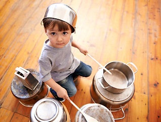 Image showing Portrait, boy child playing drums on pots on a floor, curious and enjoying music. Face, top view and kid with pans for musical entertainment, silly and carefree in kitchen in his home on the weekend