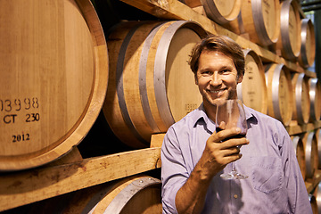 Image showing Portrait, smile and wine tasting with a man in the cellar of a distillery on a farm for the production of alcohol. Glass, industry and barrel with a happy male farmer drinking for quality control