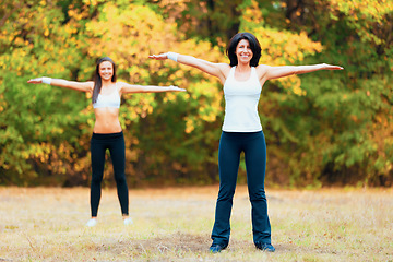 Image showing Women, arm stretching and portrait in a outdoor park for yoga and fitness. Health, wellness and arms exercise of female friends in nature on grass feeling happy with smile from body and sport