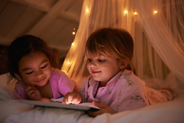 Image showing Night, bed and girls with a tablet, games and playing for fun, happiness and relax together. Female kids, children and young people with technology, entertainment and cheerful with a smile or evening