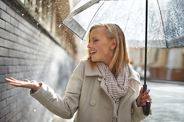 Image showing Smile, happy woman and rain feel in the city with umbrella, freedom and happiness on holiday. Winter weather, raining and urban street with a young female person on a sidewalk and vacation outdoor