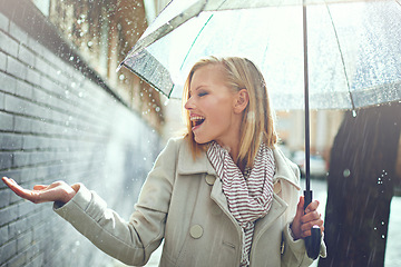 Image showing Smile, happy woman and rain feeling water in the city with umbrella, freedom and happiness. Winter weather, raining and urban street with a young female person on a sidewalk and vacation outdoor