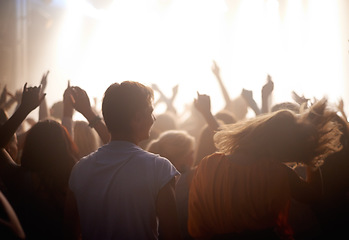 Image showing Fans, people dancing at music festival from back, stage light and energy at live concert event. Dance, fun and excited crowd in arena at rock band performance or audience at show or techno rave party