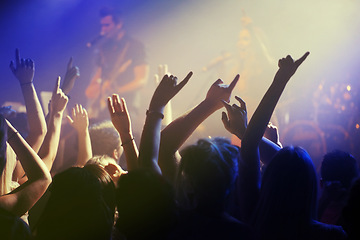 Image showing Hands in air, people dancing at concert or music festival with neon lights and energy at live event. Dance, fun and excited crowd of fans in arena for rock band, musician performance and spotlight.