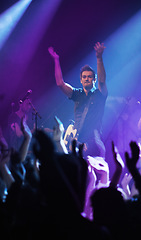 Image showing People hands, music and singer at concert in night performance, rock band or gen z in neon lights or cheers. Musician man on stage at disco event and fans clapping, crowd or audience dancing on floor