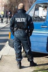 Image showing Police man, van and security in the city of Denmark for street safety, service or law enforcement patrol. Back of male officer standing ready to fight crime for justice or riot control in urban town