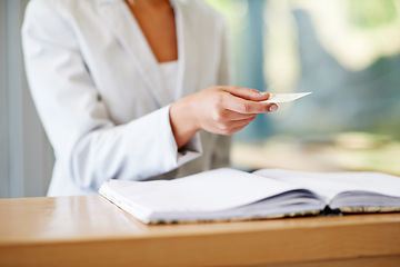 Image showing Woman, hands and business card at reception for information, gift or payment on desk at resort. Hand of female receptionist giving voucher at counter for discount, paying or check in at appointment