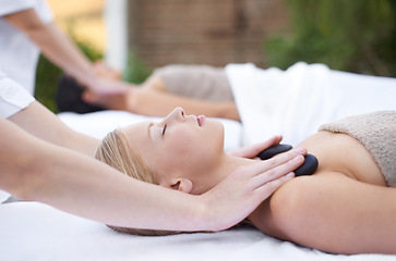 Image showing Woman at spa, hot stone massage and hands of masseuse, healing holistic treatment with zen at wellness resort. Rocks on body, peace and calm with physical therapy, alternative medicine and self care