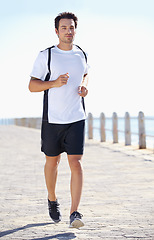 Image showing Man, fitness and running by the beach for workout, exercise or training in the nature outdoors. Fit, active or athletic male runner exercising on the ocean coast for run, healthy cardio and wellness