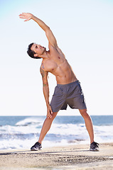 Image showing Fitness, man and stretching body on beach getting ready for exercise, workout or training in nature. Fit, active or muscular male exercising in warm up stretch for healthy cardio or wellness by ocean