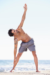 Image showing Fitness, man and stretching body on beach for yoga or getting ready for exercise, workout or training in nature. Fit, active or muscular male yogi in warm up stretch, cardio or exercising by an ocean