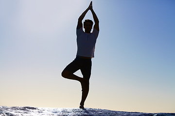 Image showing Man, silhouette and yoga in meditation on beach for spiritual wellness, inner peace or mental wellbeing in nature. Calm male yogi in tree pose for balance, healthy body or mindfulness by the ocean