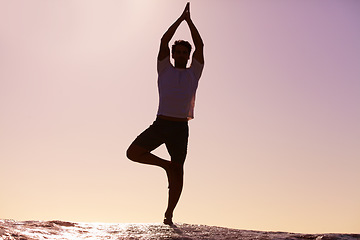 Image showing Man, silhouette and yoga in sunset meditation on beach for spiritual wellness, inner peace or mental wellbeing in nature. Male yogi in tree pose for balance, healthy body or mindfulness on ocean rock