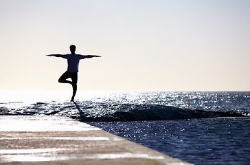 Image showing Man, silhouette and yoga in meditation on beach rock for spiritual wellness, inner peace or mental wellbeing in nature. Male yogi in tree pose for balance, healthy body or mindfulness on the ocean