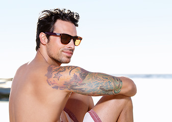 Image showing Tattoo on body, young man at beach and with sunglasses sitting. Summer vacation or holiday break, freedom or traveling and happy male person relaxing at the seashore with glasses in sunshine