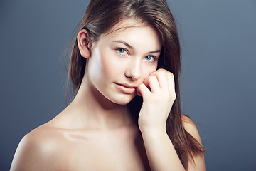 Image showing Natural, face and portrait of a shy woman in studio with a glow, beauty and cosmetics. Headshot of a young female model on a grey background for shine, hair care and facial skincare or dermatology