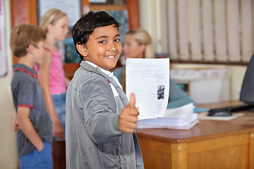 Image showing Portrait, child and student with thumbs up and paper for test or assignment in classroom. Happiness, hand gesture and kid with like emoji, agreement and learning in elementary school for education.