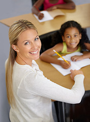 Image showing Kid, teacher and portrait in classroom studying school work for an education with support. Woman, smile and desk with child to help with reading or learning for children to work at school building.