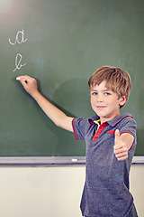 Image showing Portrait, child writing and thumbs up on blackboard in classroom, elementary school and mockup. Chalkboard, education student and kid with hand gesture for like emoji, agreement and learning to write