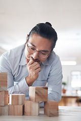 Image showing Man in startup with building blocks, thinking of vision, games and design innovation for office or construction. Engineering, architecture and Asian designer with wood block for problem solving game.