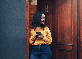 Image showing Doorway, woman and phone for social media, texting and happy while reading message in front of house. Smartphone, influencer and african female online for blog, networking or property app review